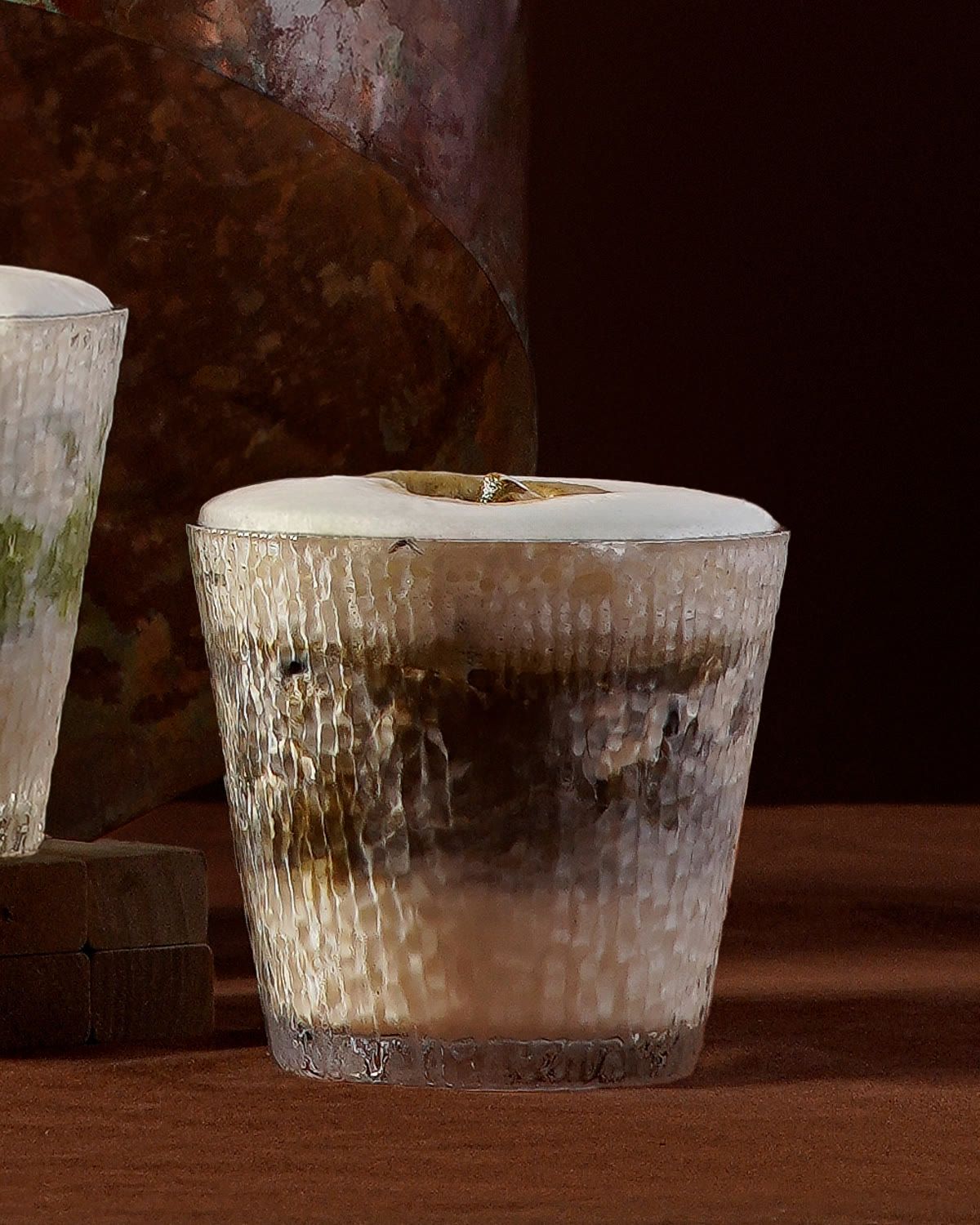 Ly hojicha latte thủy tinh mờ với các lớp trà rang và sữa.